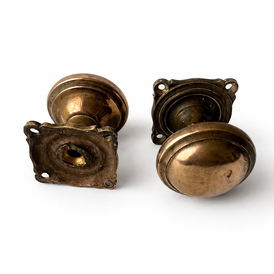 Pair of heavy antique cast brass door knobs with round handles, square backplates