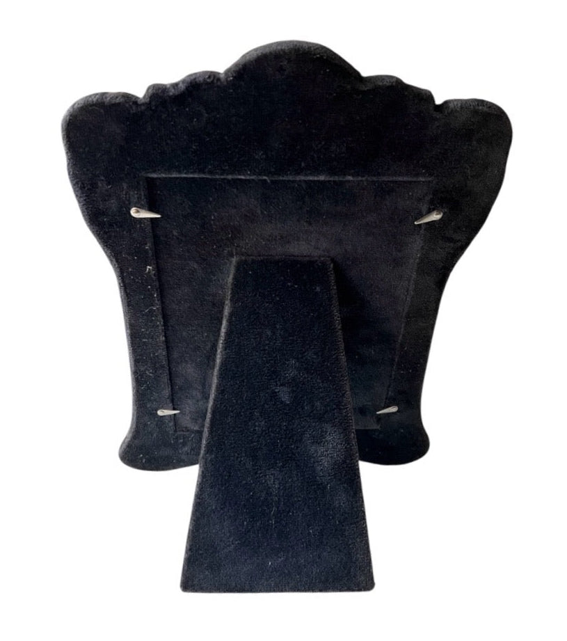 Black velvet back of sterling silver photo frame it is shown on a white background.