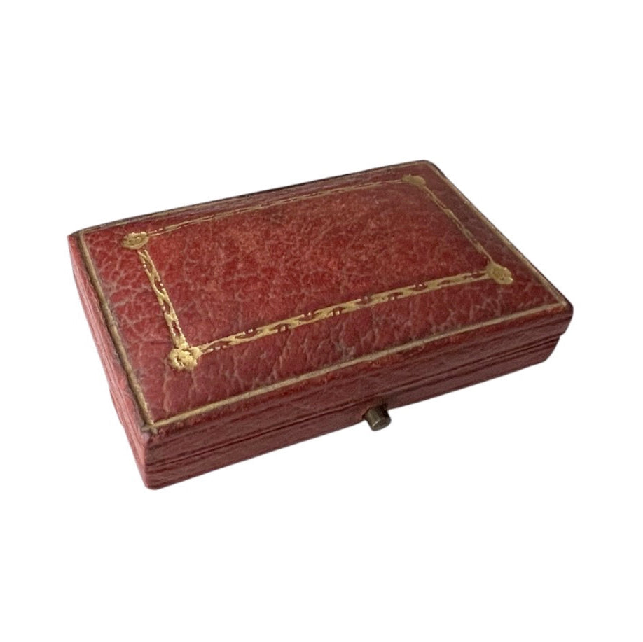 Antique rectangular red leather case with gold trim and corner accents, shown on a plain white background.