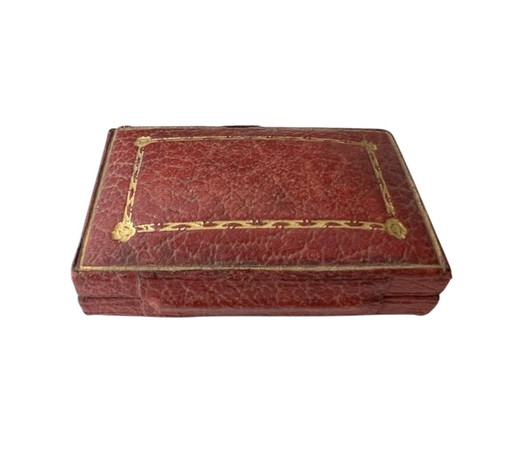 Antique rectangular red leather case with gold decorative border detailing on the lid, shown against a plain white background.
