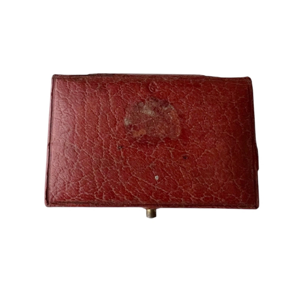 Antique rectangular red leather case with gold decorative border detailing on the lid, shown against a plain white background.