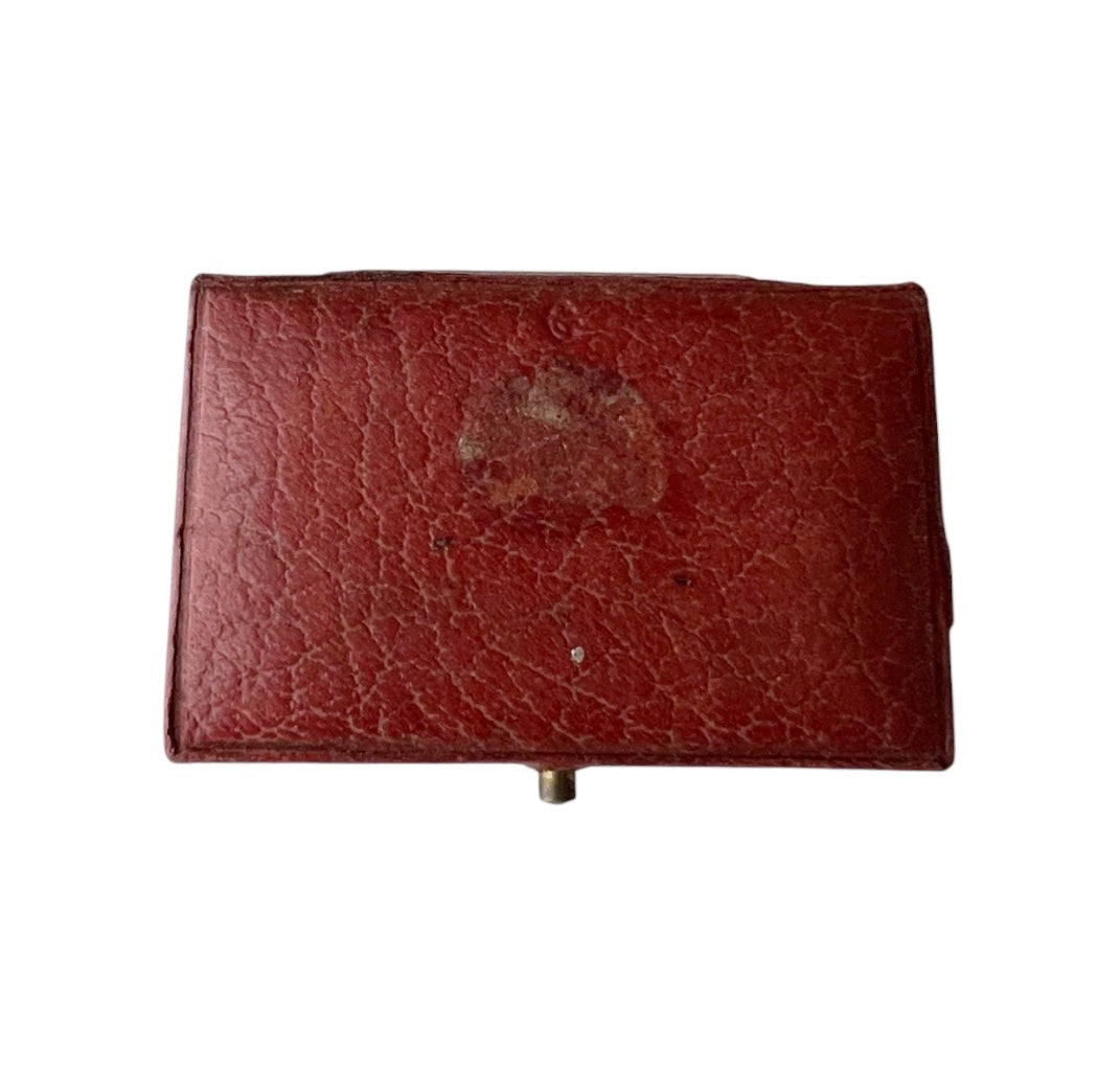 Antique rectangular red leather case with gold decorative border detailing on the lid, shown against a plain white background.