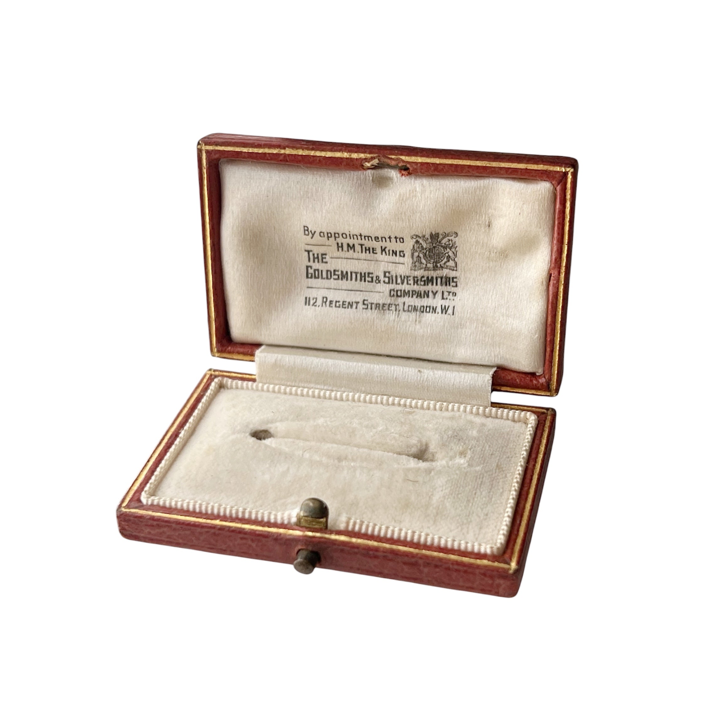 An open antique leather brooch box with cream velvet lining, displaying a silver pin and an interior label reading 'The Goldsmiths' Company.'.